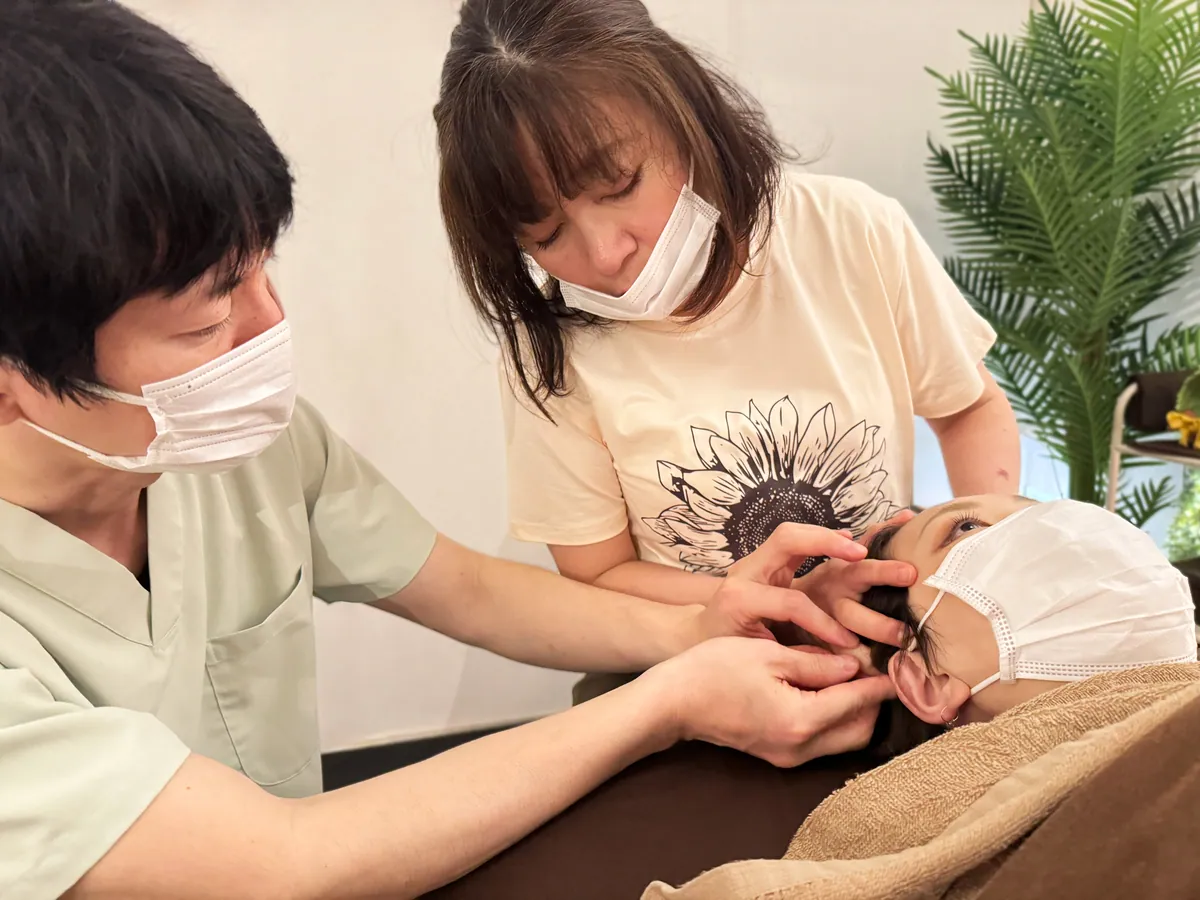 講師と受講生が受けモデルへの手の当て方を確認する個別講座の様子